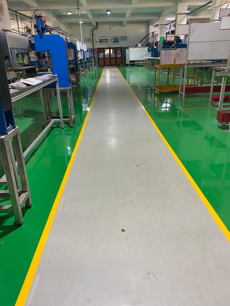 Green epoxy flooring with walkway marking in an industrial assembly shop